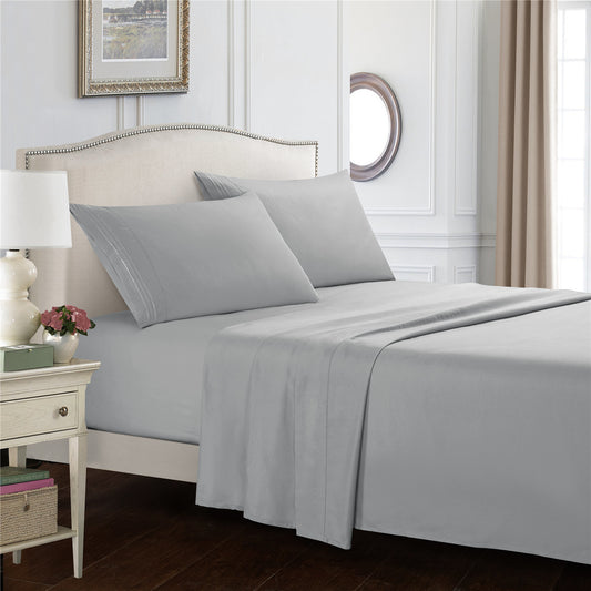 Gray bedding set on a bed in a bedroom with a side table and decor items.
